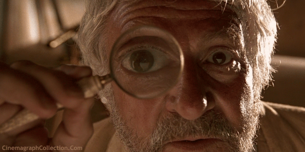Un uomo anziano, guardando attentamente con una lente.