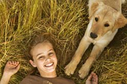 Foto de uma menina feliz acordando junto ao seu cachorro